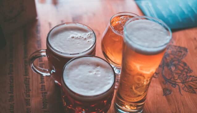 clear glass mug and beer can on brown wooden table