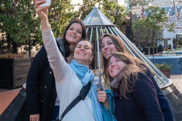 four women taking selfie near tipi tent