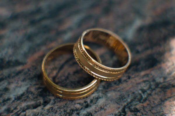 Two gold wedding rings sitting on top of a table