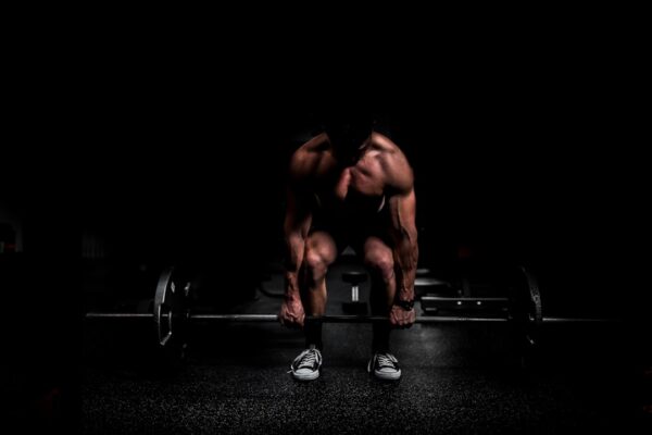 shirtless man lifting barbell in gym
