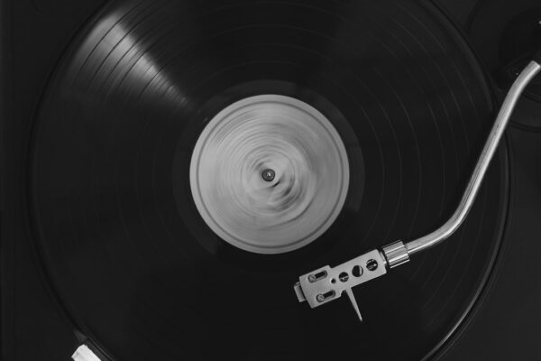 A black vinyl record spinning on a turntable with a silver tonearm
