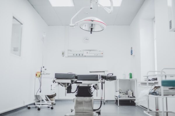 An operating room with a surgical table, overhead light, and medical equipment