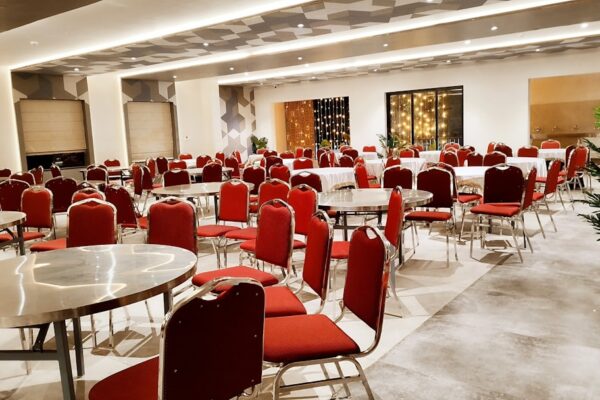 Empty banquet hall with red chairs and round tables