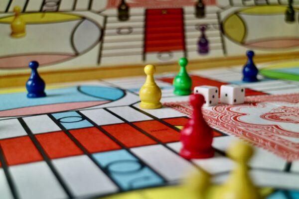 Colorful plastic game pieces and two white dice on a board game