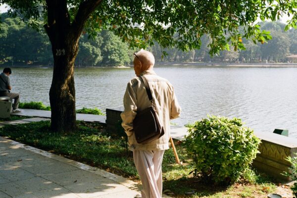 Elderly man walking by a lake in a park